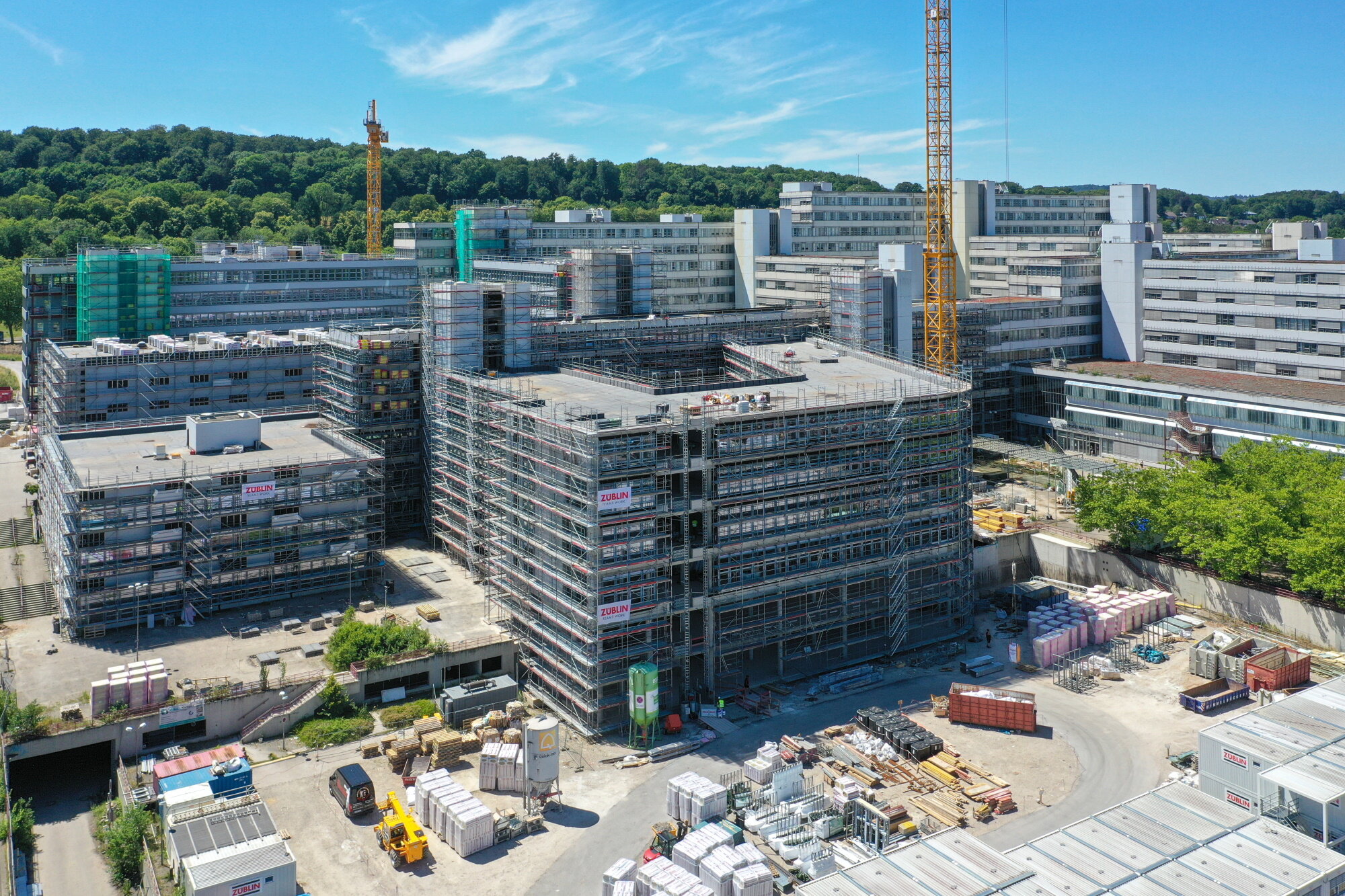 Vor dem Gebäude der Universität Bielefeld ist ein eingerüsteter Neubau zu erkennen, der sich an den Bestand anschließt.